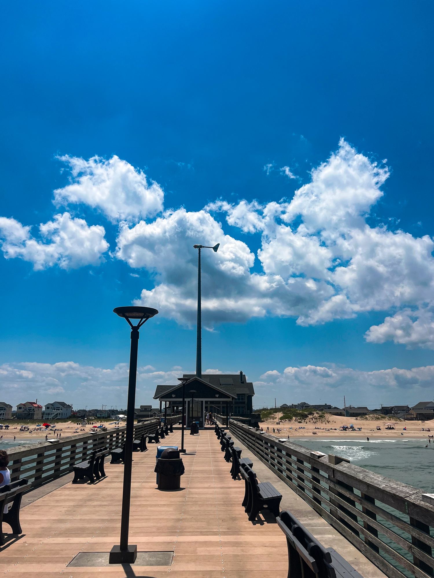 Looking down the deck of Jennette's Pier under a bright blue sky